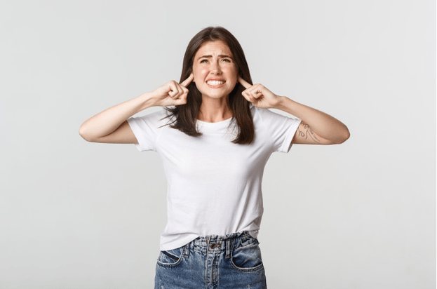 A woman shutting her ears because she is annoyed by the noise.
