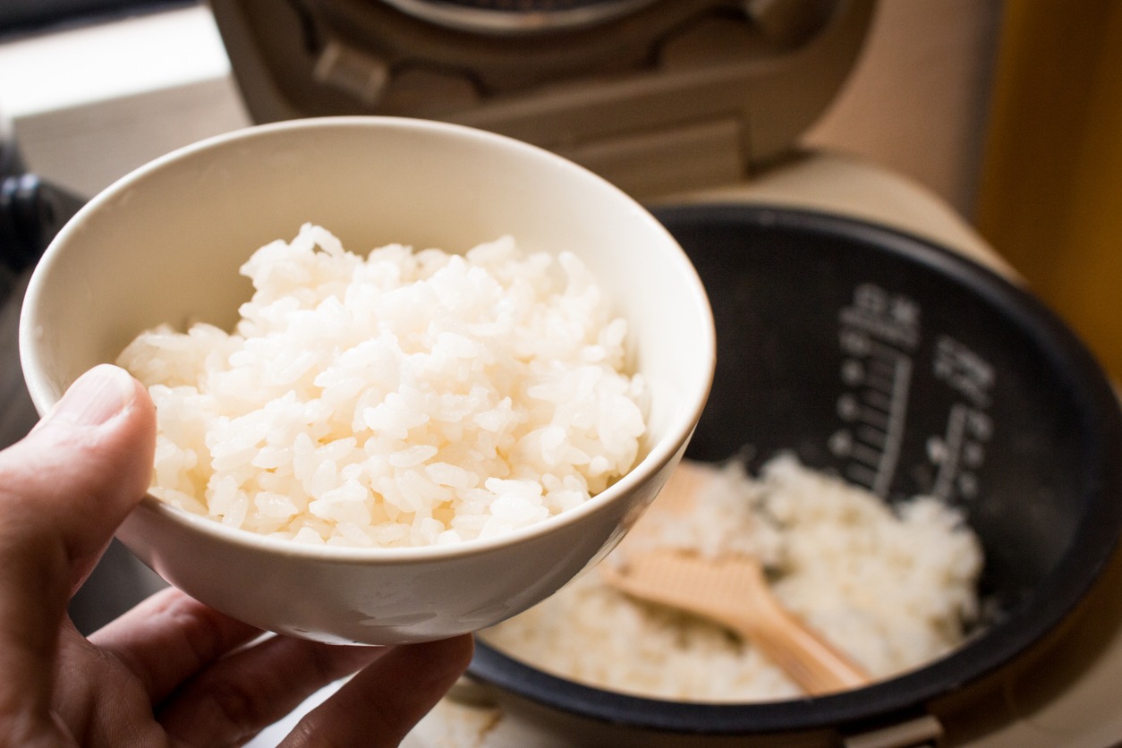 Japanese steamed rice in bowl with rice cooker.