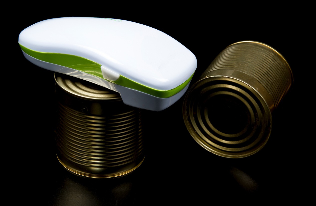 Electric can opener and canned good isolated on black background